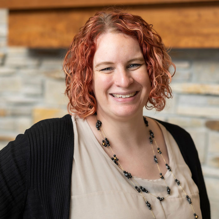 headshot of amanda rombough wearing tan shirt and black cardigan