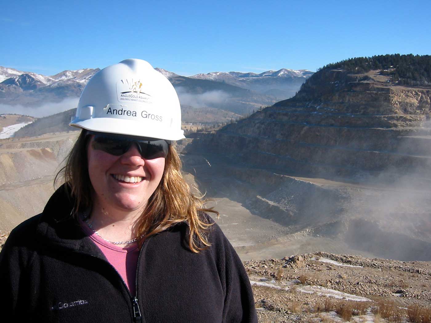 woman wearing a hard hat and black coat standing in mine