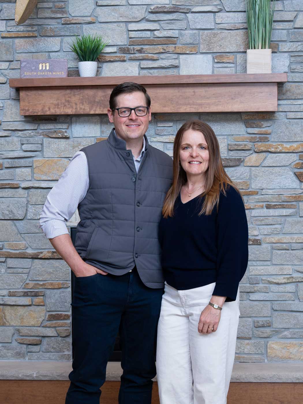 a couple standing in front of a fireplace