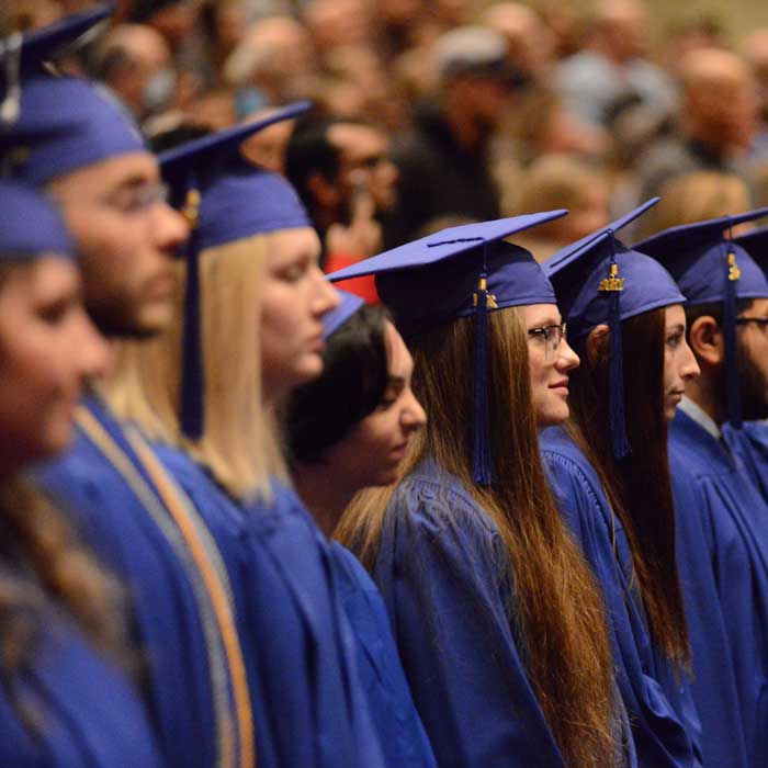 students in blue robes and caps lined up at college graduation
