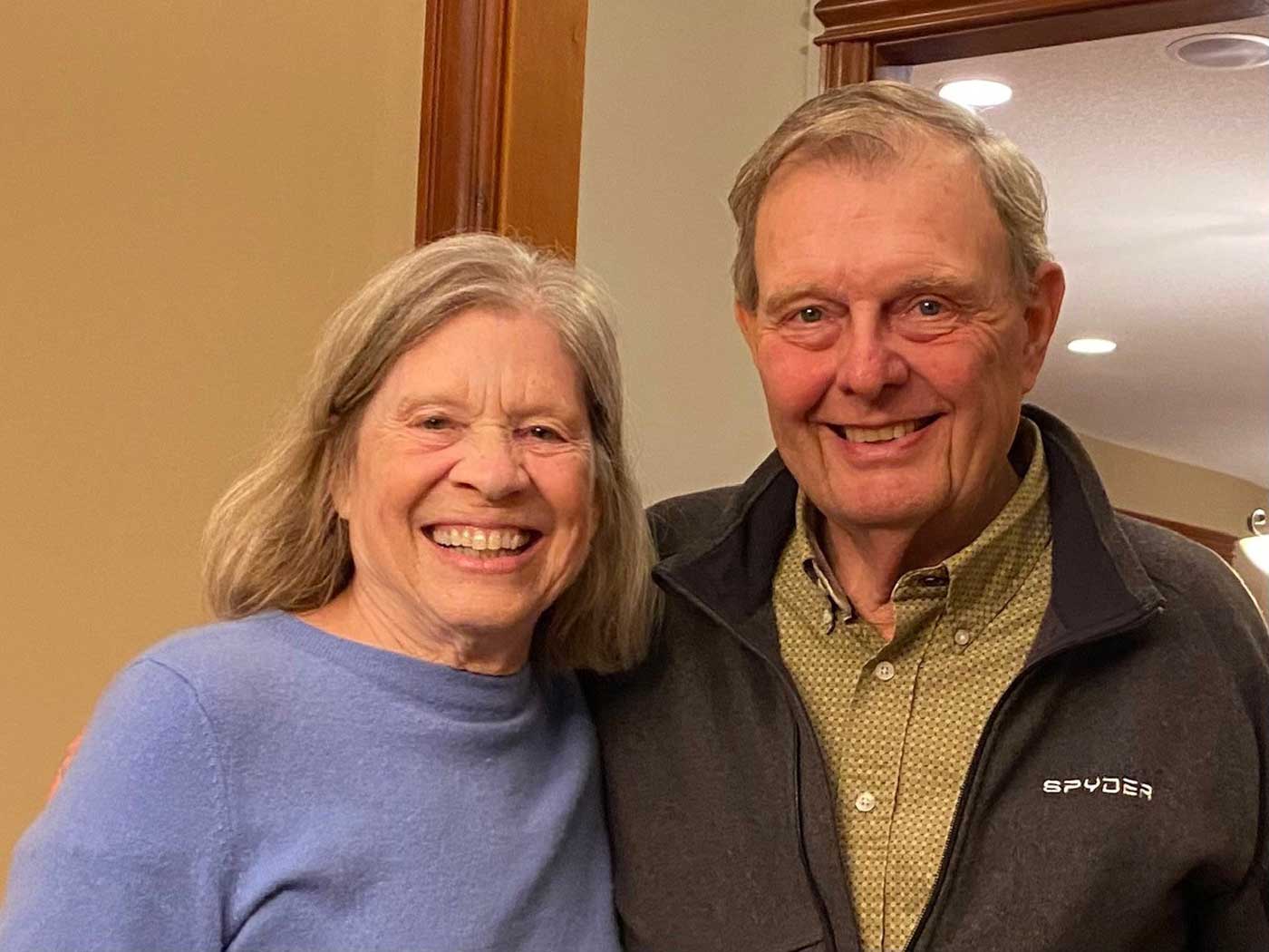 Howard-Noziska-2-web husband and wife smiling at camera in front of a wall