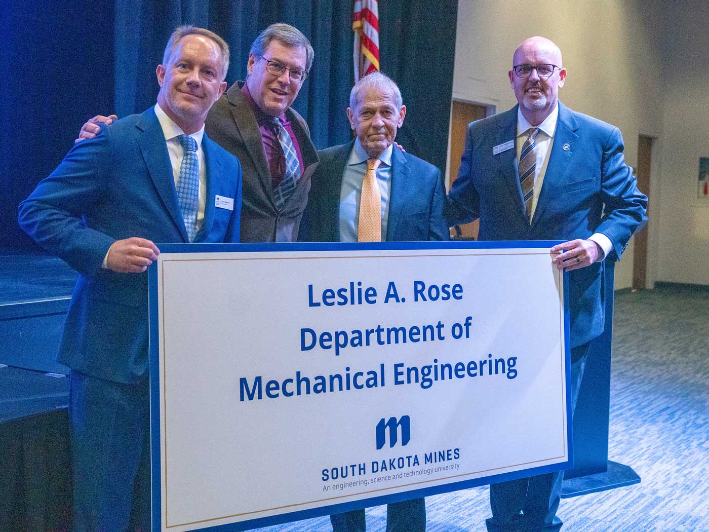 Les-Rose-gift-announcement-web group of men holding sign that says Leslie A. Rose Department of Mechanical Engineering