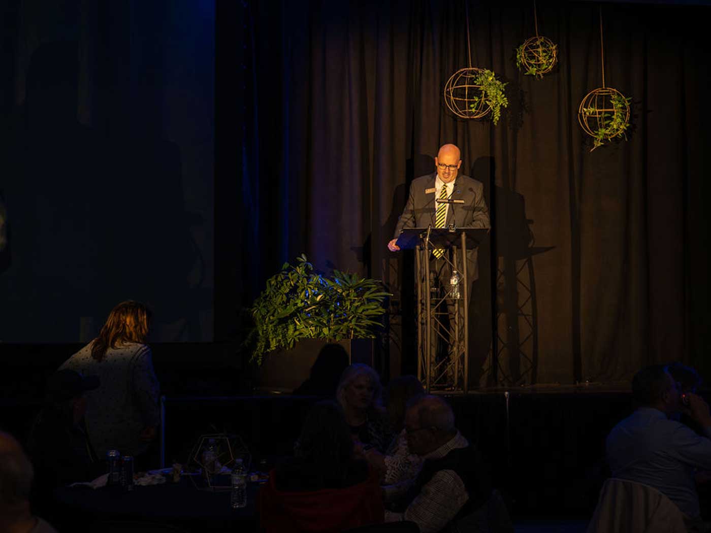 man in dark room speaking to crowd