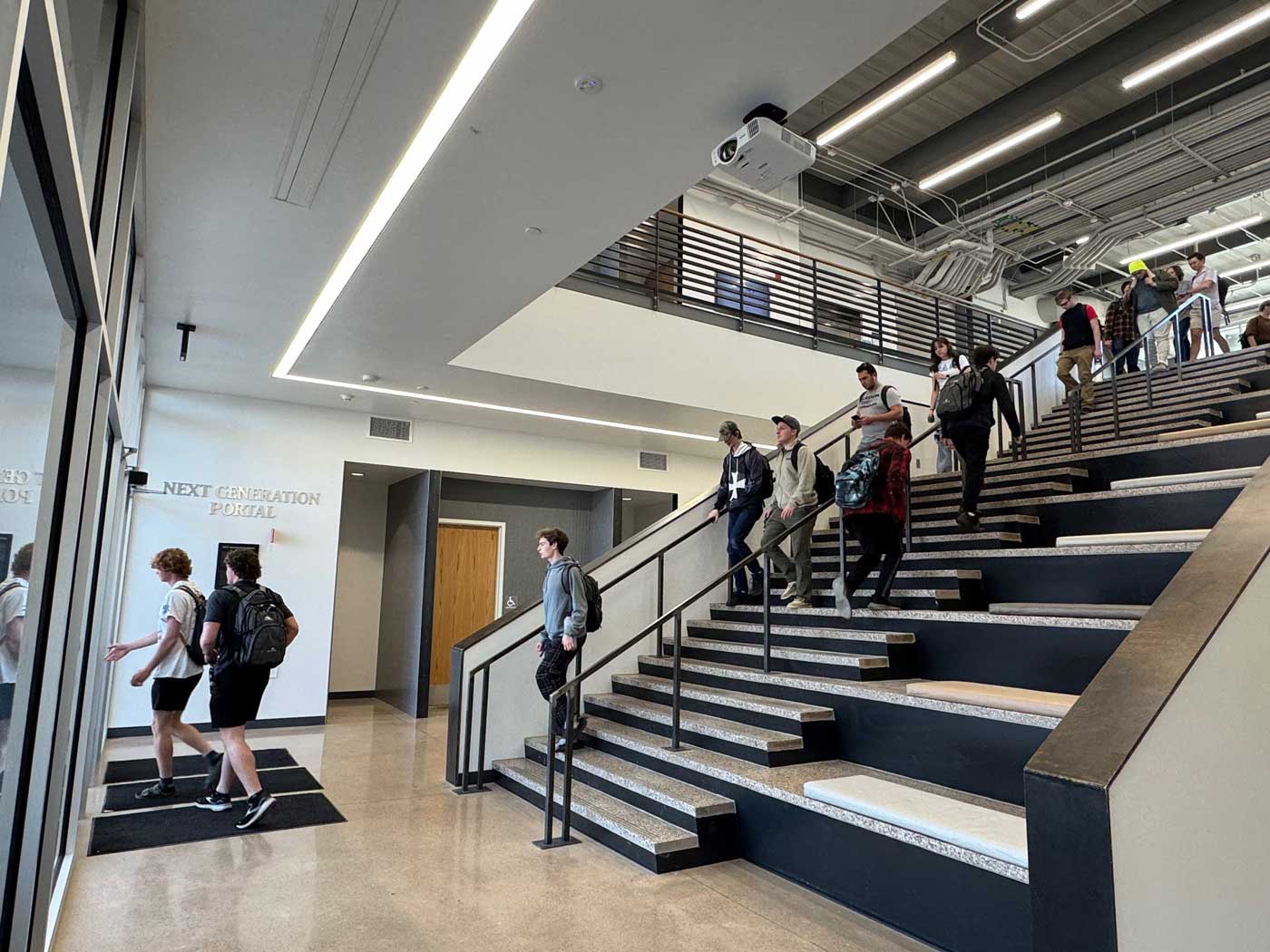 Next-Generation-Portal-web students walking up and down large set of stairs in lobby of building
