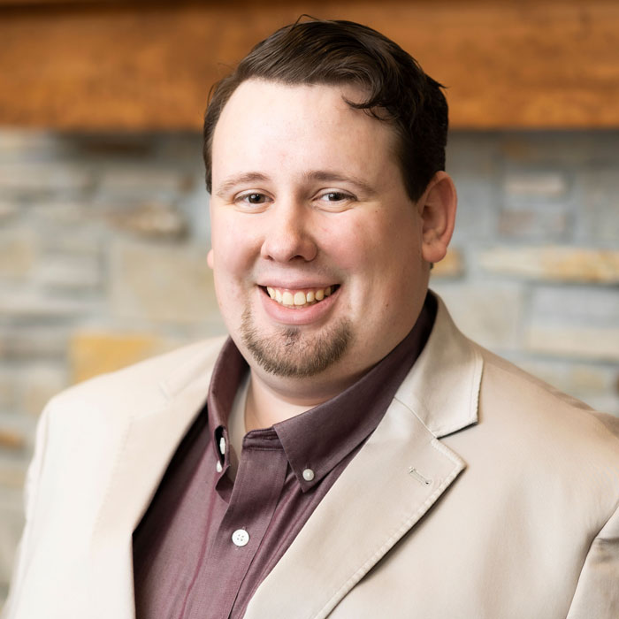 headshot of ryan bozer wearing a tan blazer and brown shirt
