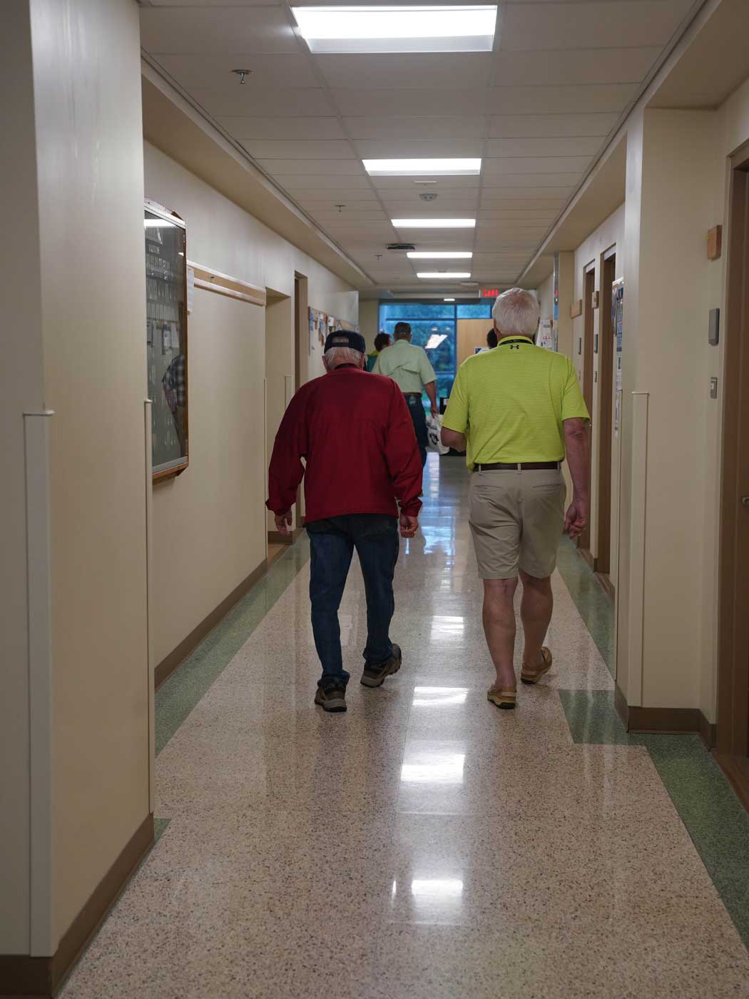 two men walking away from the camera down a school hallway