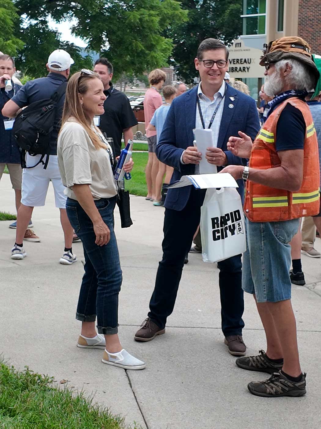 president of the university talking to alumni wearing orange vest