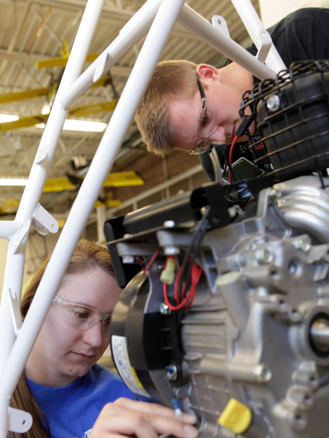close up photo of students working on fixing a baja car in a shop