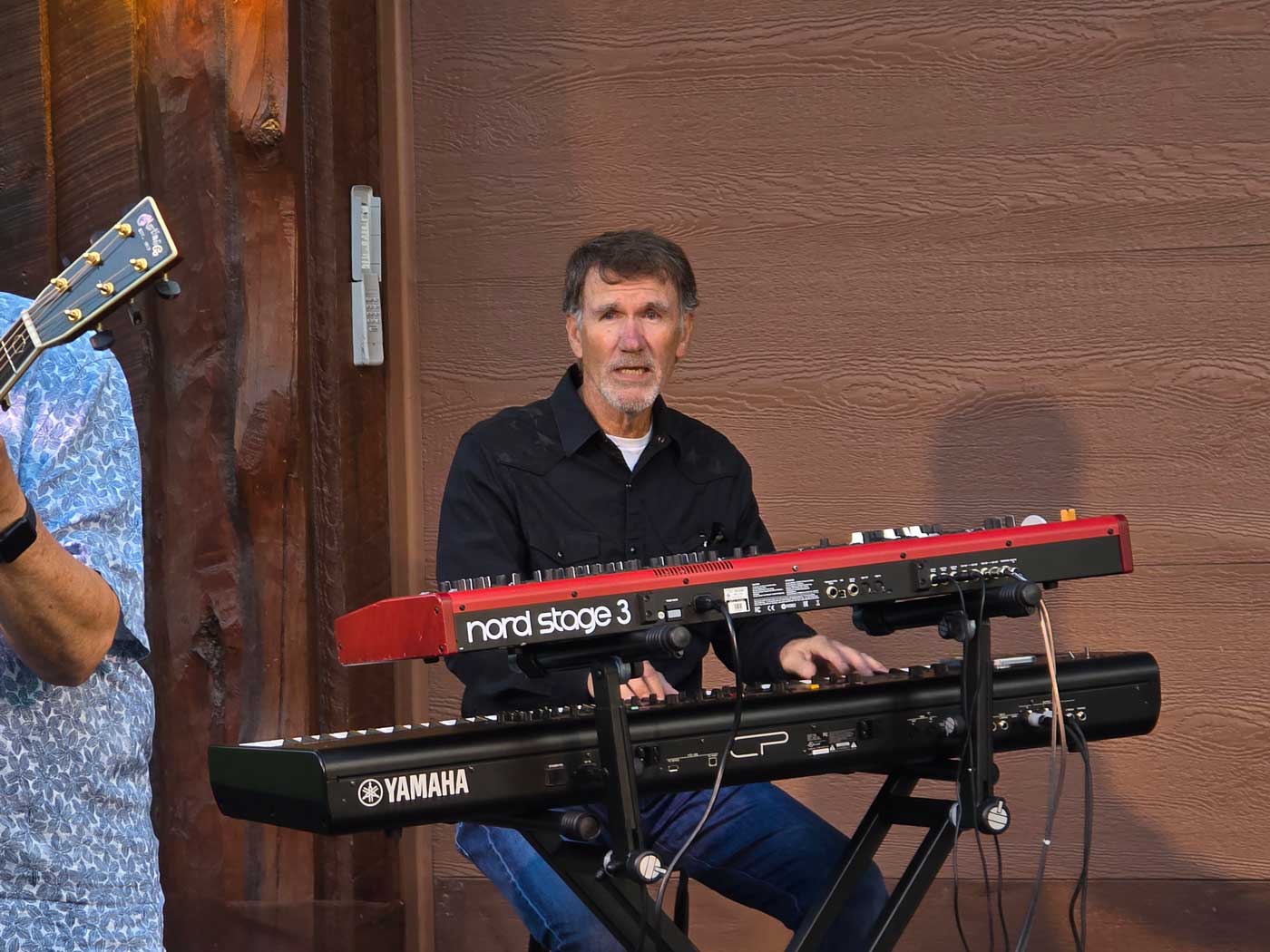 man sitting down playing two electric keyboards