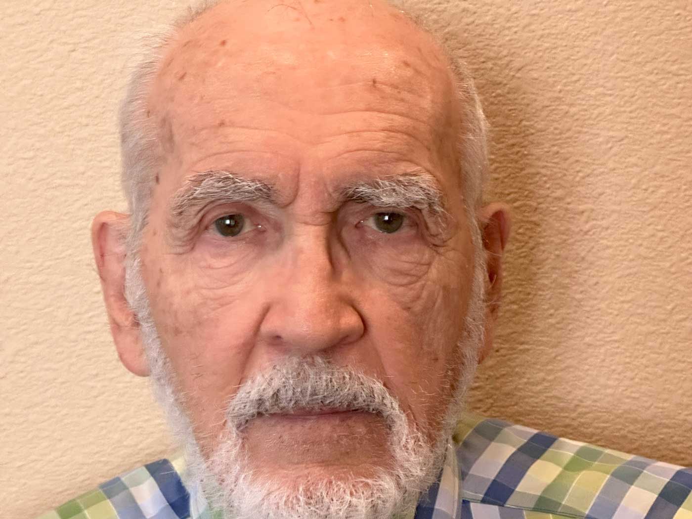 man in plaid shirt standing in front of wall