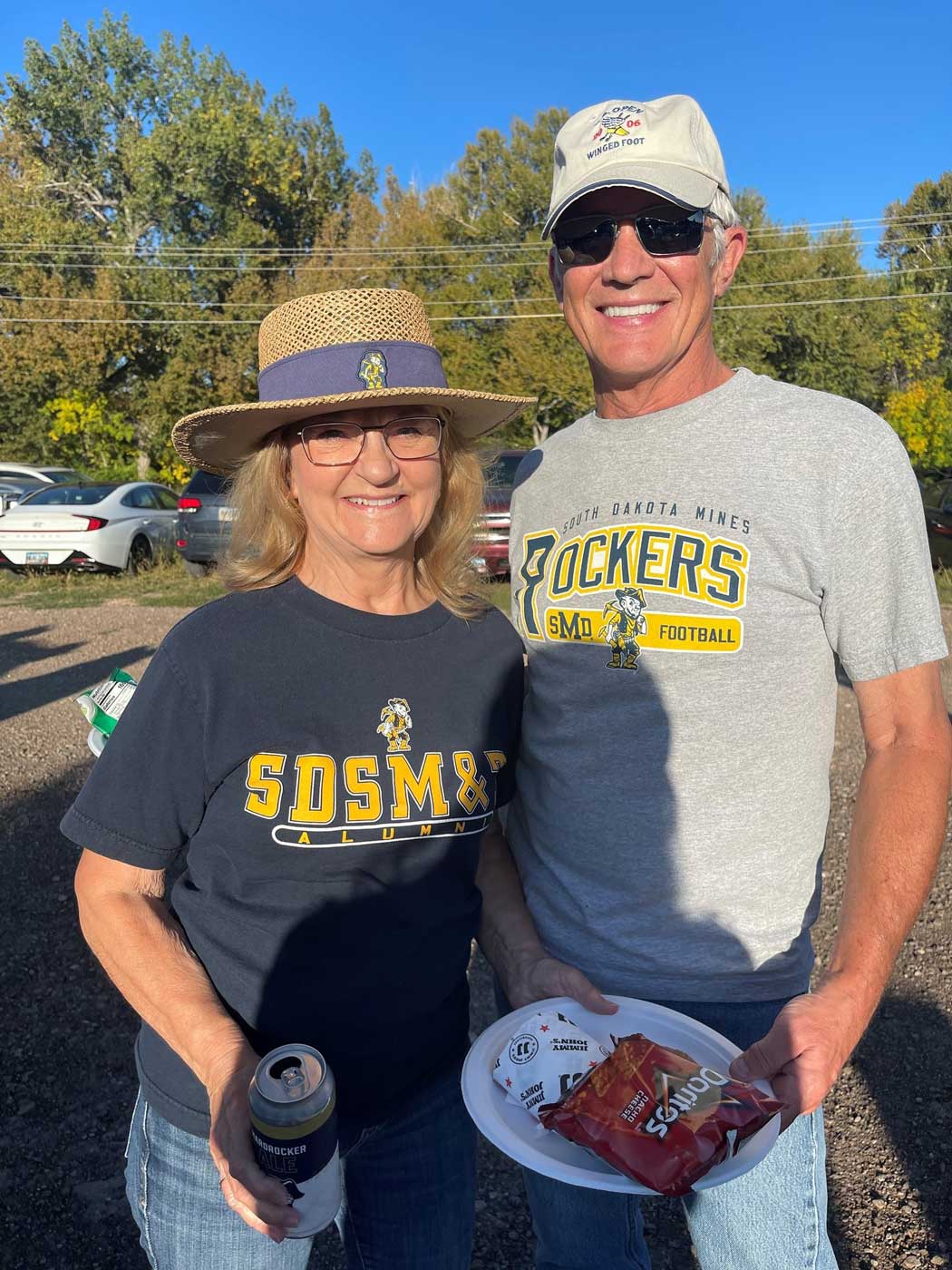 couple smiling at camera at tailgate event wearing Mines gear