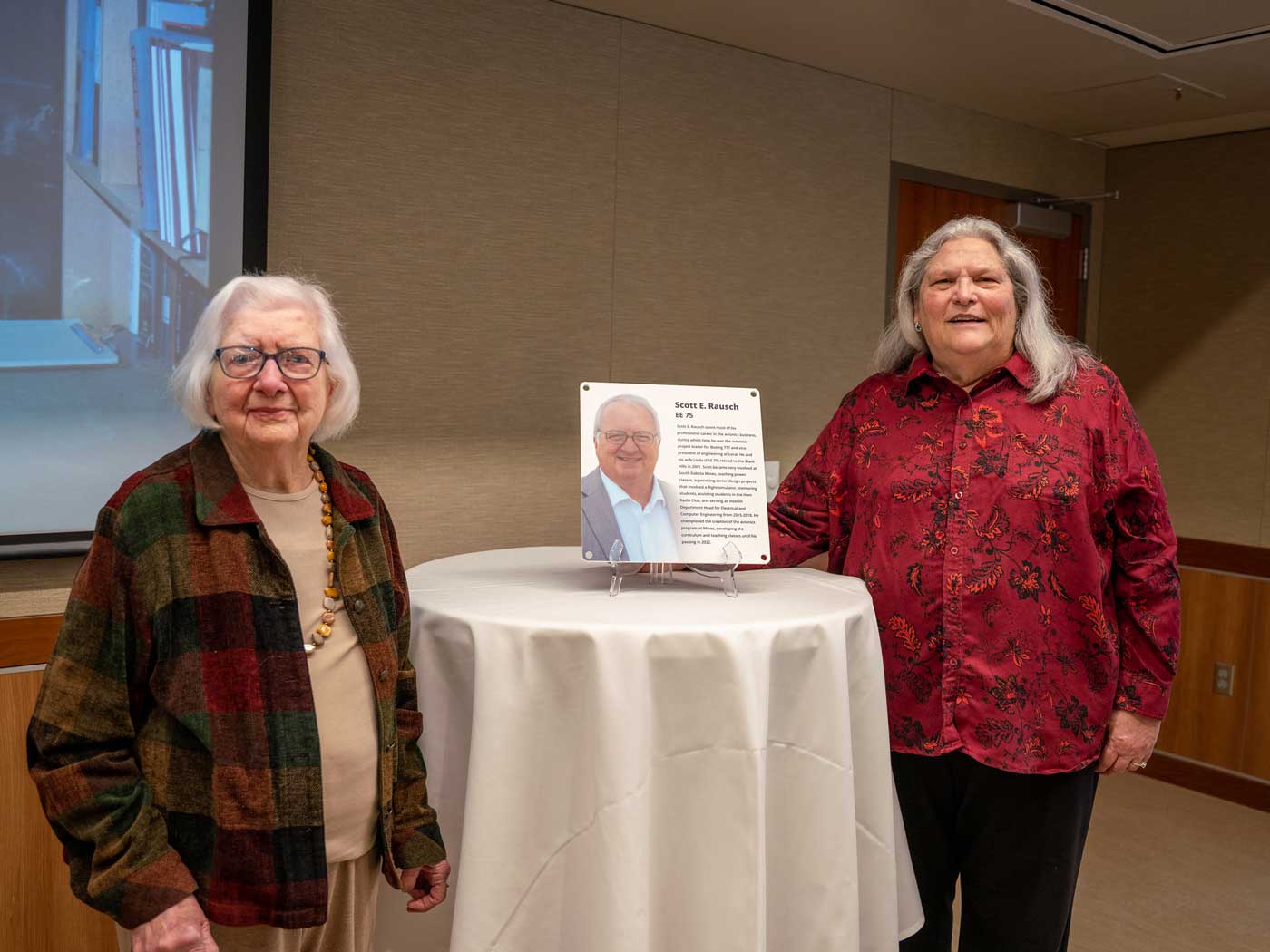 two women standing by table with memorial plaque