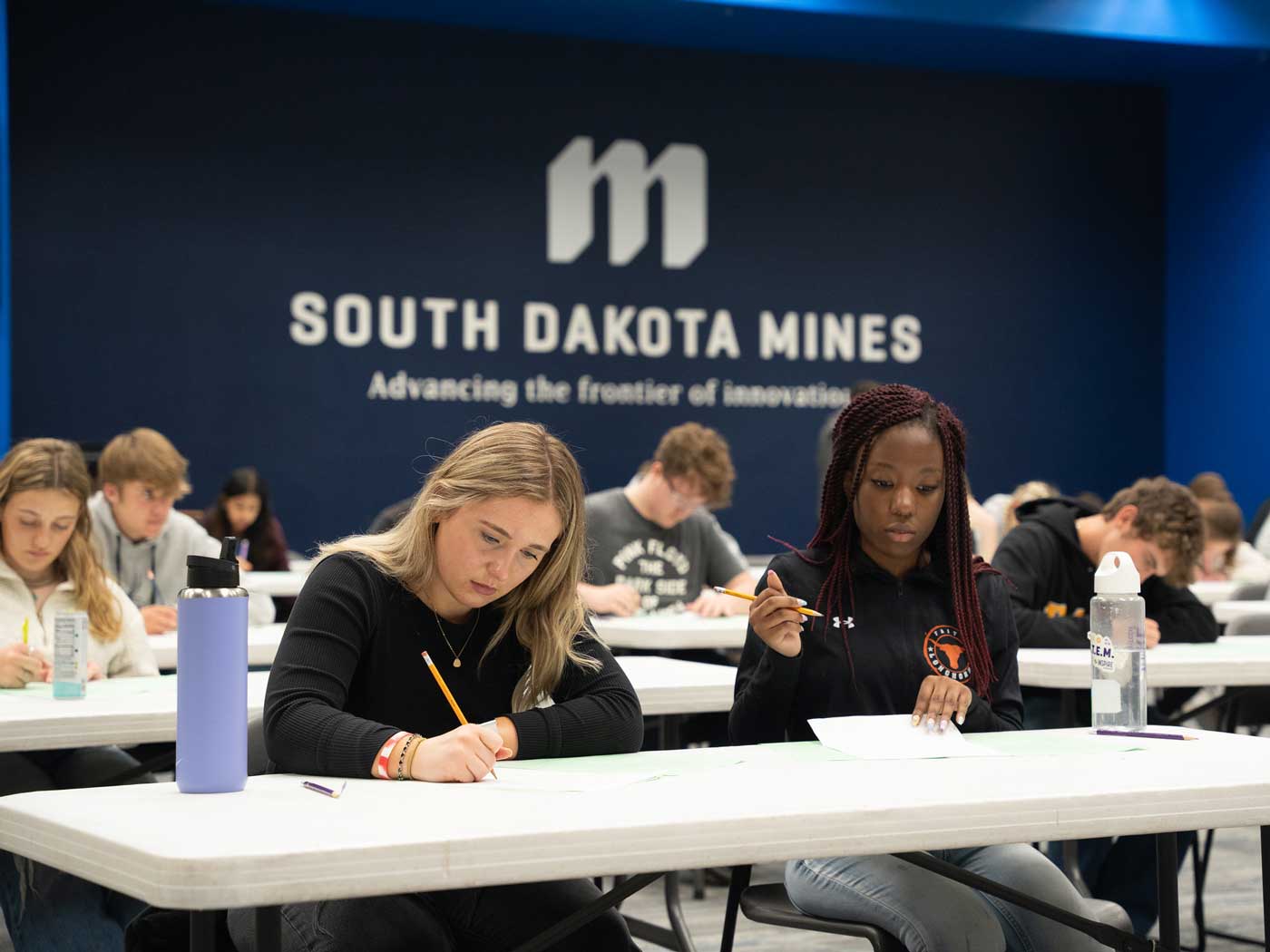 students working at a table in front of a blue wall