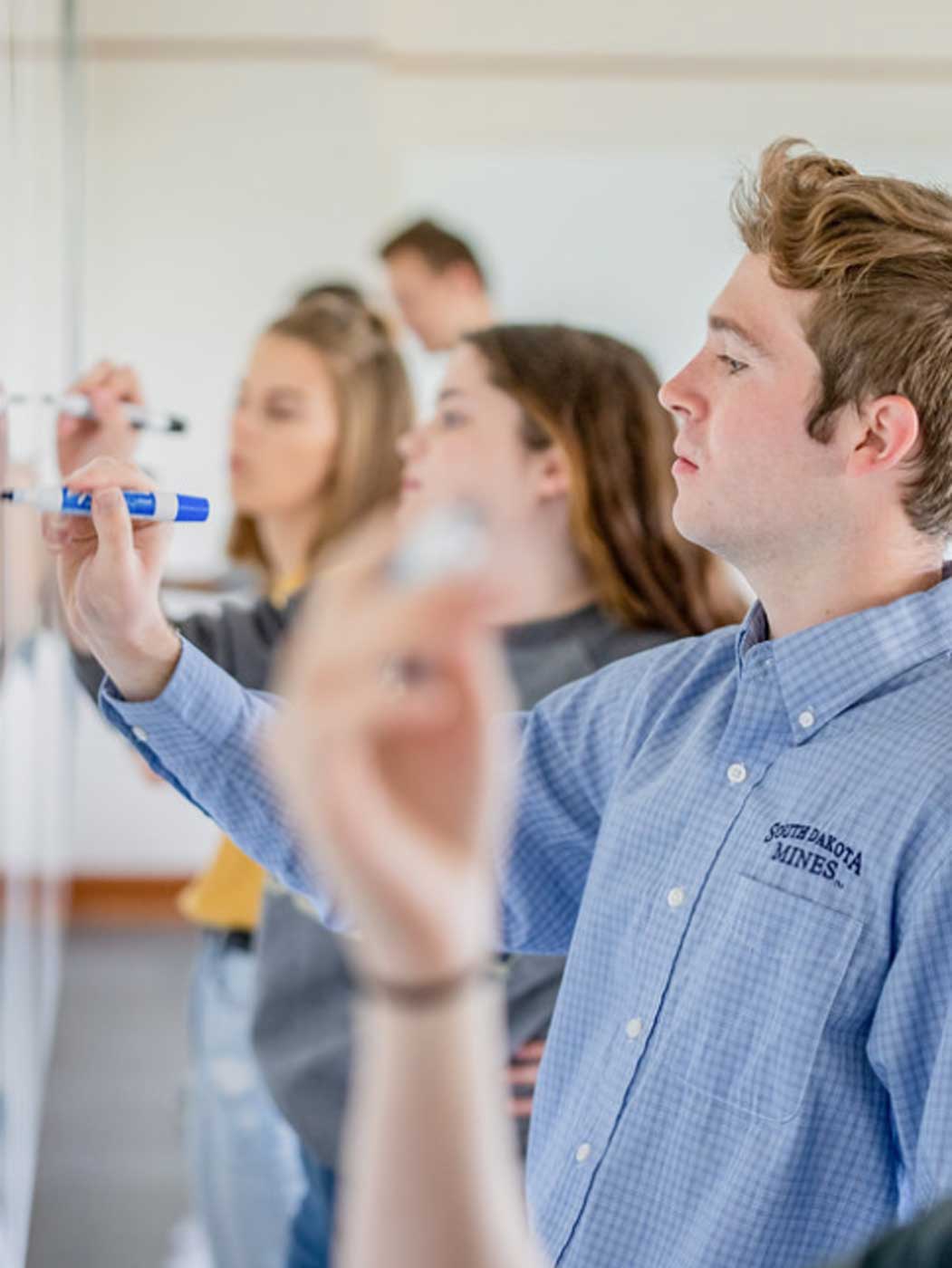 students writing on a dry erase board with markers