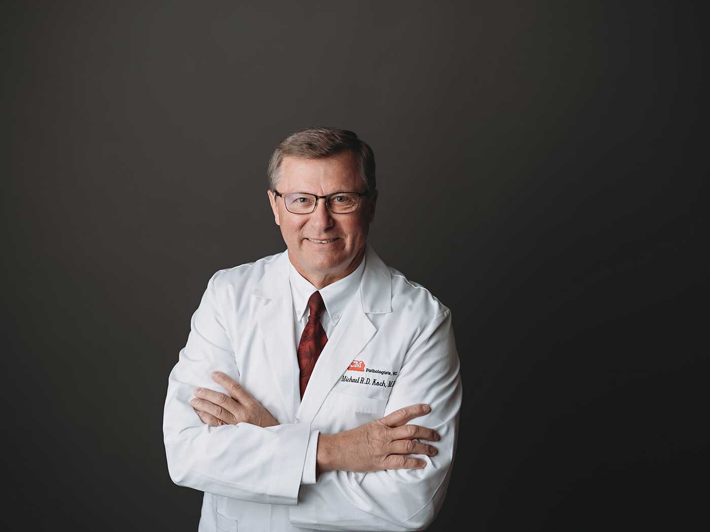 mike-koch-photo-web headshot of man wearing glasses in medical coat and red tie